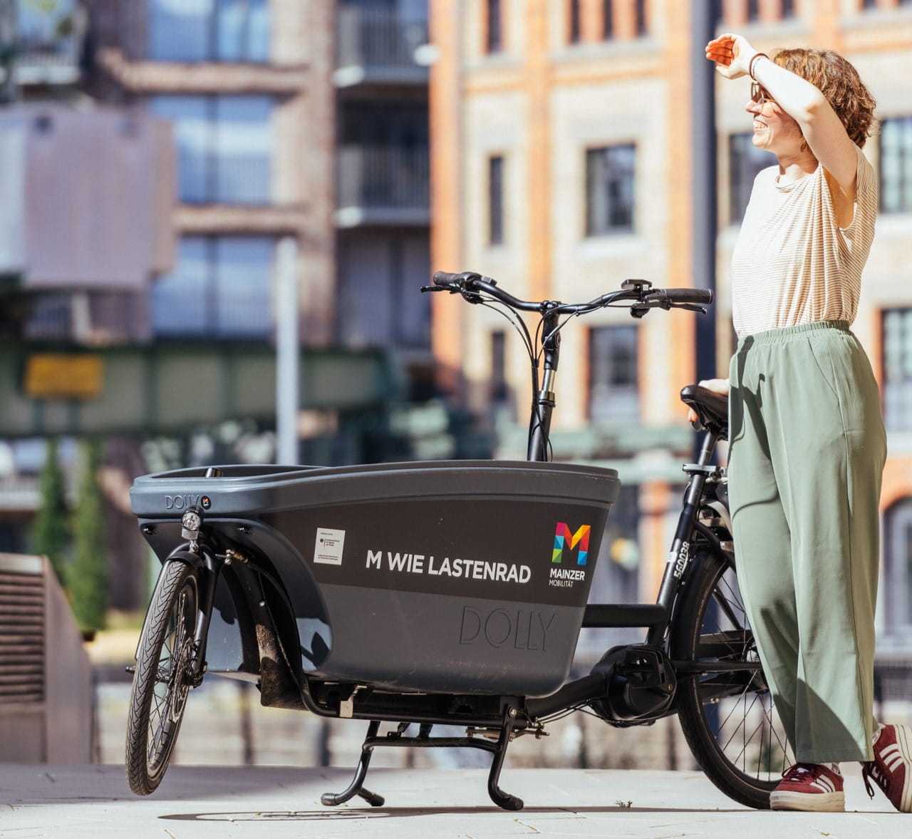Foto einer Frau am Zollhafen, die neben einem Lastenrad steht
