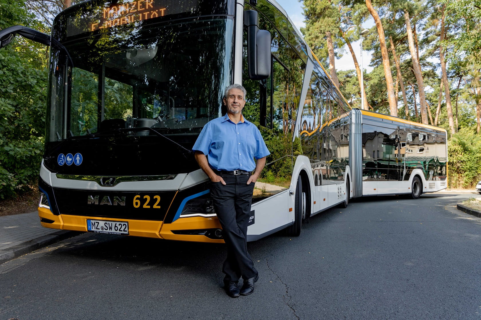 Busfahrer lehnt vorne an seinem Bus