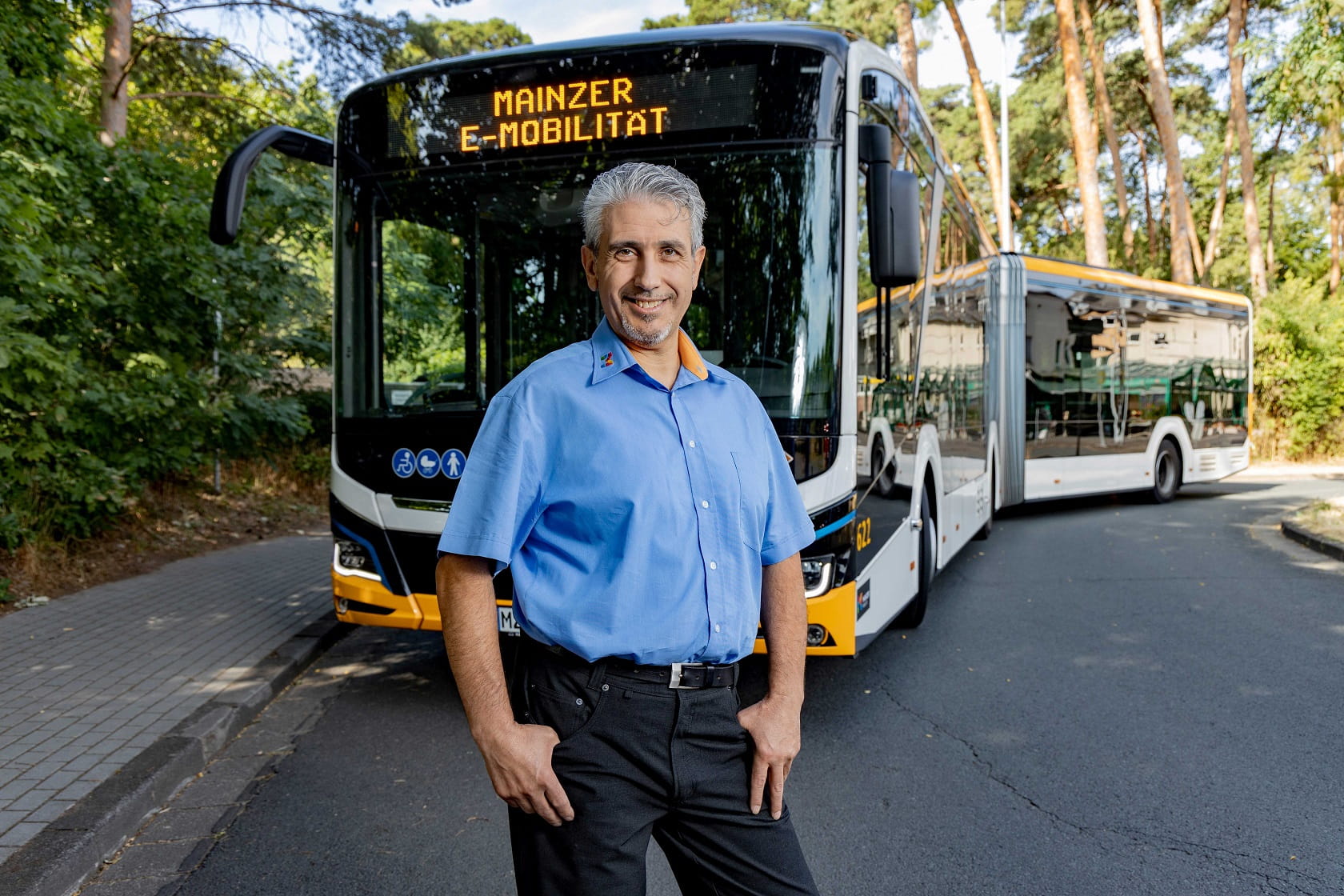 Busfahrer steht vor dem Bus und lächelt