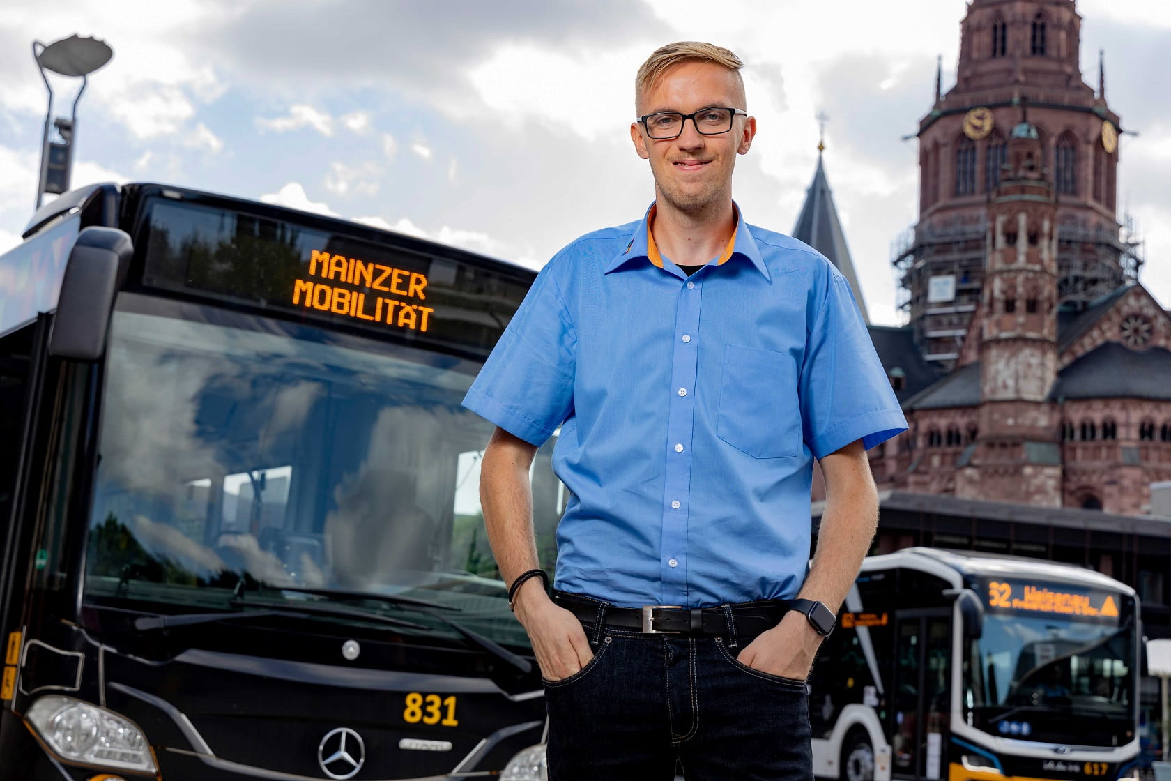 Busfahrer steht vor seinem Bus, es ist der Mainzer Dom zu sehen