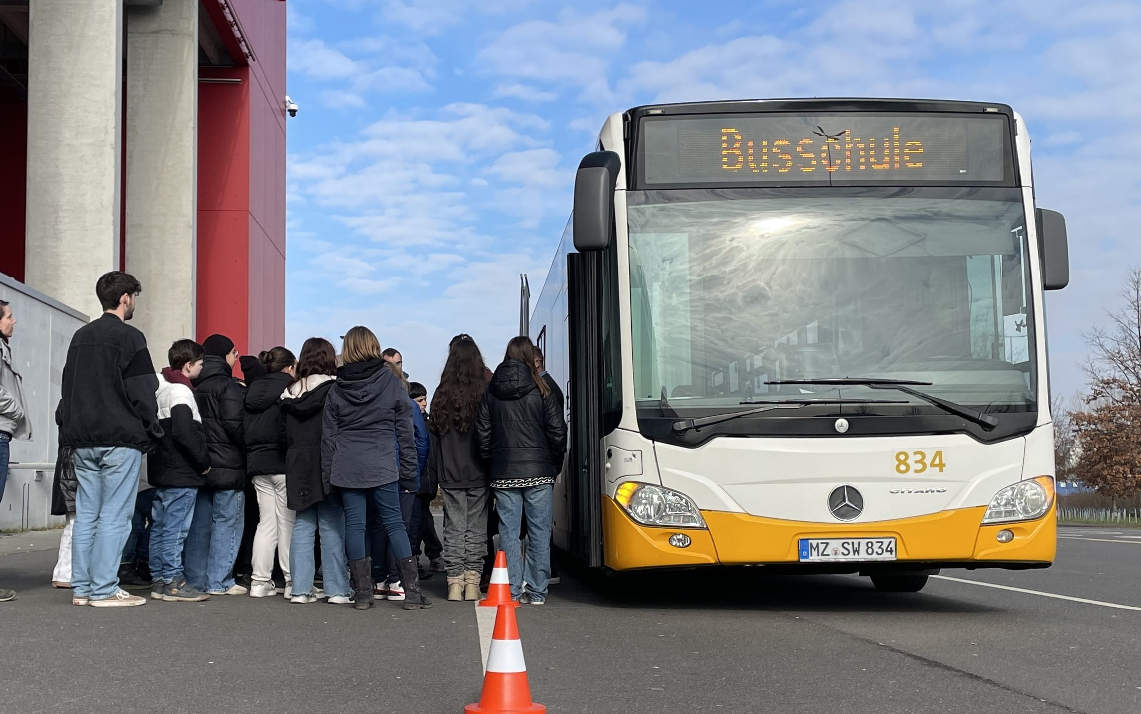 Eine Schlange von einsteigenden Kindern vor der Tür eines Busses mit der Zielbeschilderung Busschule