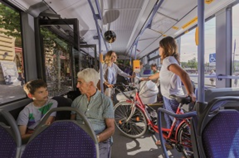 Im Bus befinden sich eine Fahrradfahrerin und eine Mutter mit Kinderwagen
