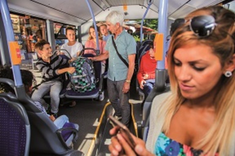 Ein älterer Herr bittet einen jungen Mann darum, seinen Rucksack vom Sitzplatz zu nehmen