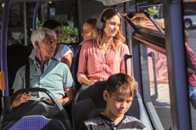 Eine junge Dame sitzt im Bus und hört Musik mit Kopfhörern