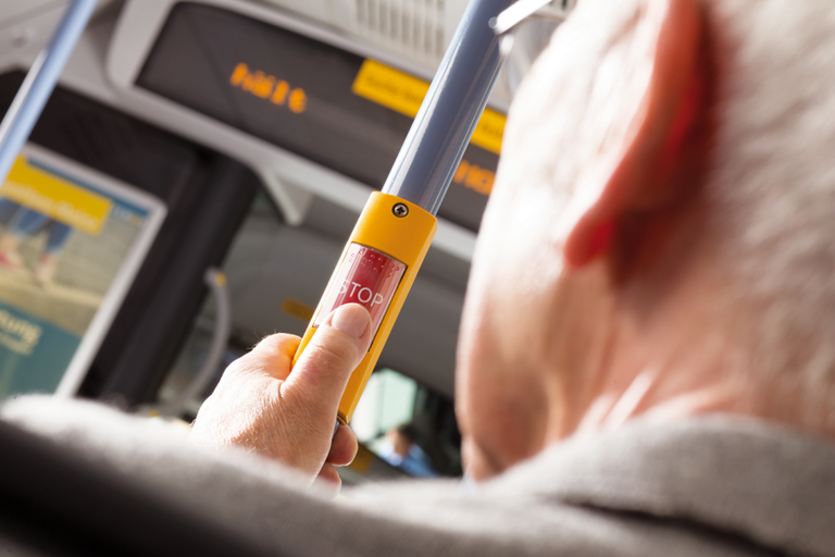 Nahaufnahme einer Hand, die einen Stopp-Knopf für den Haltewunsch drückt