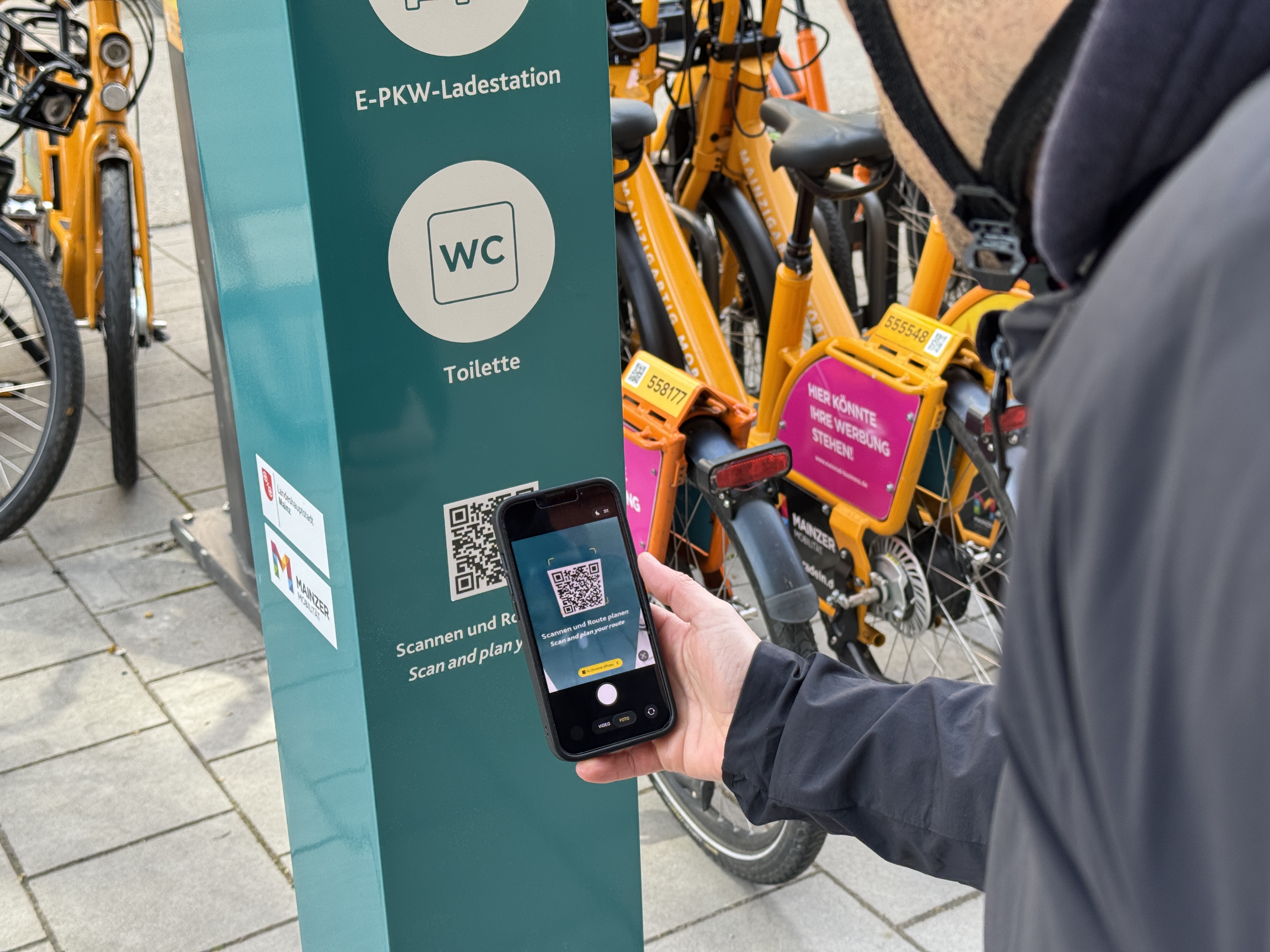 Bild mit Person, die den QR-Code an der Mobilstation scannt